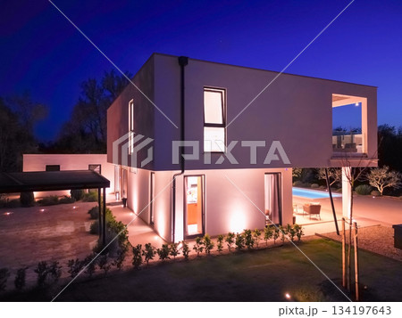 Modern luxury villa illuminated at night with pool, terraces, and contemporary architecture. Warm lighting and elegant outdoor living create a stylish and sophisticated atmosphere 134197643