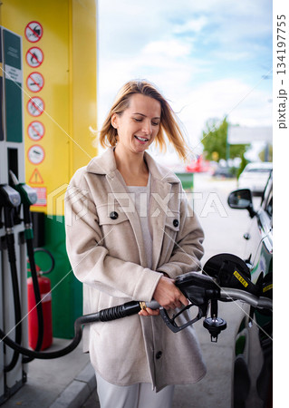 Woman smiling fueling diesel car at gas station 134197755