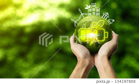 Hands holding a glowing green globe with a battery and leaf icon, surrounded by outlines of wind turbines and eco buildings, representing bio energy and sustainable living. Concept of Bio Energy Hands holding a glowing green globe with a battery and leaf icon, surrounded by outlines of wind turbines and eco buildings, representing bio energy and sustainable living. Concept of Bio Energy 134197808