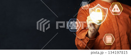Person hand interacting with a virtual shield icon with a padlock, representing data protection and security, surrounded by legal and compliance icons. Concept of Data Privacy Enforcement 134197815