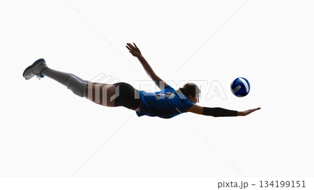 Female volleyball player diving with elevated legs reaching toward ball. 134199151