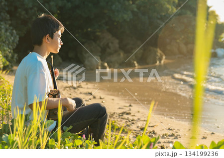 海辺で三線を奏でる中学生 134199236