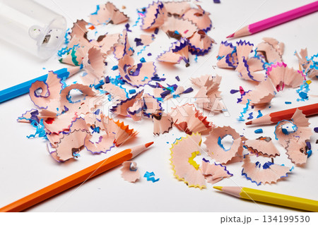 Colorful pencil shavings with drawing pencils and a sharpener on a white background 134199530