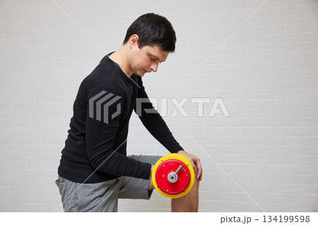 Man holding dumbbell in hand, reflecting on home exercise 134199598