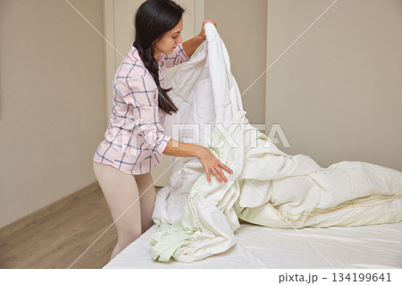 Woman making her bed, tidying up bedroom for a fresh start to the day 134199641