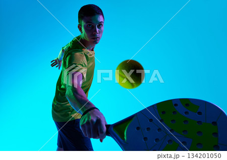 Padel athlete forward strike neon depth shot. Padel athlete forward strike neon depth shot. 134201050