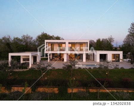 Modern luxury villa illuminated at night with pool, terraces, and contemporary architecture. Warm lighting and elegant outdoor living create a stylish and sophisticated atmosphere 134202838