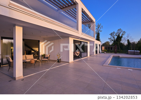 Modern luxury villa with pool, terrace, and minimalist architecture on a sunny day. Clean lines, large windows, and outdoor living spaces create a stylish contemporary home setting 134202853