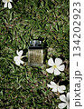 Original organic photo transparent perfume bottle flatlay on green grass white floral background Original organic photo transparent perfume bottle flatlay on green grass white floral background 134202923