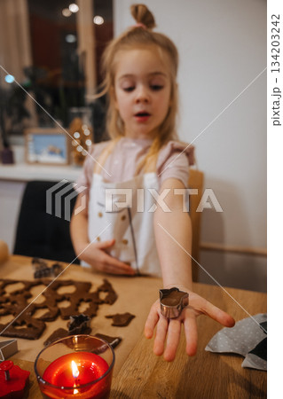 Child makes shapes with cookie cutters during baking activity at home in the evening 134203242