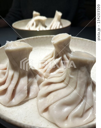 Georgian khinkali dumplings on round plates. Vertical food photo 134203509