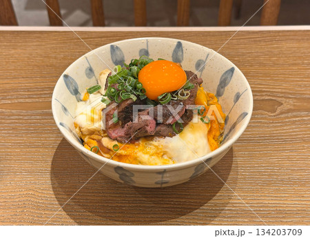 Delicious beef bowl with raw egg yolk and green onions on a wooden table 134203709