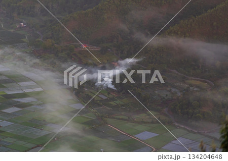 Smoke plume above vast rice fields, foggy Lombok valley. 134204648