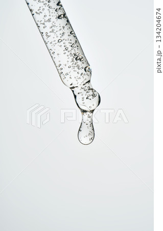 Dropping cosmetic serum from glass pipette applicator 134204674