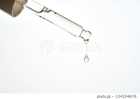 Cosmetic pipette dispensing a liquid serum drop 134204676