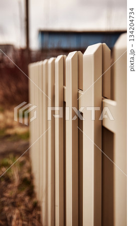 Close-up of modular fence panels in a sand color, highlighting geometric patterns and panel joints. This design creates a modern and stylish outdoor boundary 134204734