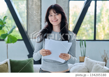 Smiling young woman with business study important papers standing in home interior 134205180
