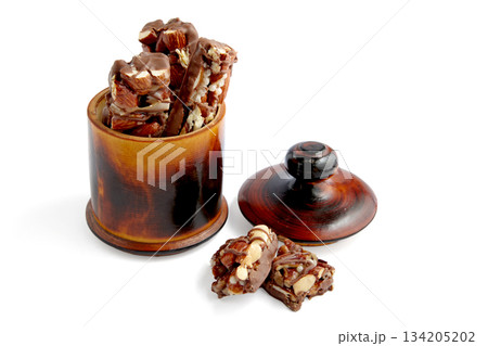 Sweet nutty caramel bars covered with chocolate in a wooden bowl. Sweet nutty caramel bars covered with chocolate in a wooden bowl. 134205202