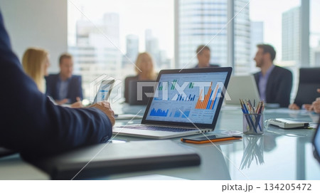 Team members collaborating in a modern office with digital analytics on display during a meeting 134205472