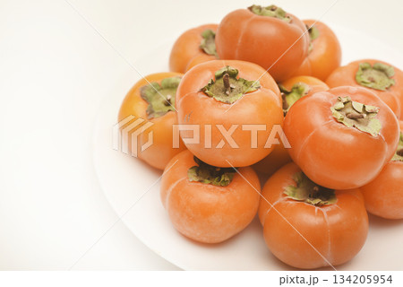 Orange persimmon fruits. Ripe persimmon on a plate. Orange persimmon fruits. Ripe persimmon on a plate. 134205954