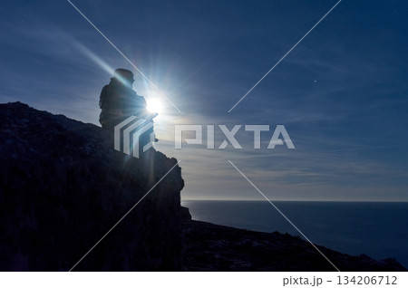 Buddha figure on some rocks, under the moonlight, on the sea Buddha figure on some rocks, under the moonlight, on the sea 134206712