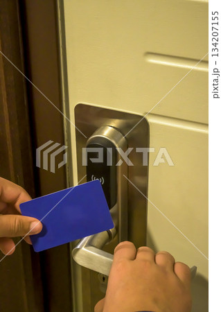A hand holding a blue card key near a hotel door lock in a long hallway, key electronic lock, hotel room, holidays in mallorca, spain A hand holding a blue card key near a hotel door lock in a long hallway, key electronic lock, hotel room, holidays in mallorca, spain 134207155