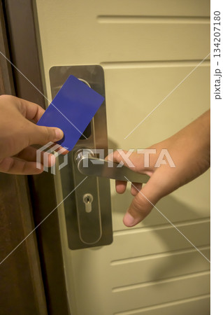 A hand holding a blue card key close to a hotel door lock, key electronic lock, hotel room, holidays in mallorca, spain 134207180