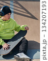 young, teenager, with skateboard sitting on the track, with headphones 134207193