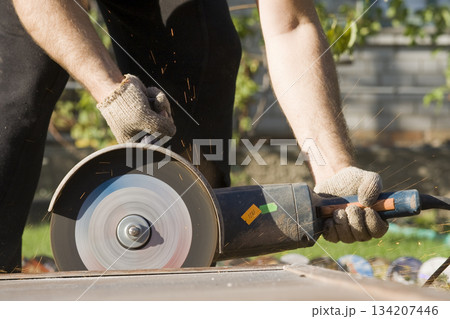 Closeup of worker hands with angle grinder Closeup of worker hands with angle grinder 134207446