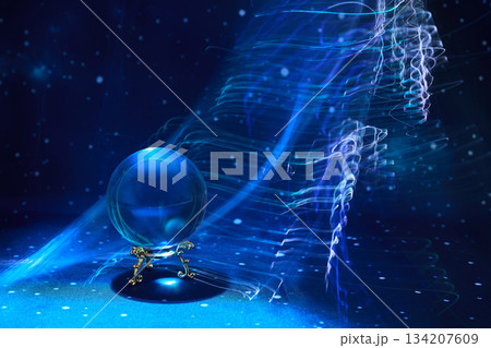 Mystical Light Orb. A glowing crystal ball sits on a stand amidst swirling blue light 134207609