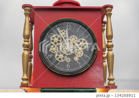 The clock is five to twelve. Vintage red clock with golden details showing five minutes to midnight on New Year's Eve. Concept of countdown, new beginnings, festive celebration The clock is five to twelve. Vintage red clock with golden details showing five minutes to midnight on New Year's Eve. Concept of countdown, new beginnings, festive celebration 134208911
