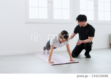 パーソナルトレーナーにトレーニングを受ける若い女性 134210090