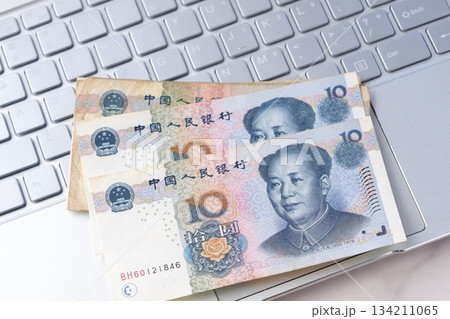 毛沢東の肖像が描かれた中国の通貨、人民元（RMB）の紙幣とノートパソコン 134211065