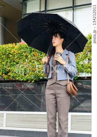 Travel woman, people person, lifestyle street business work outdoor professional holds umbrella, sips coffee, observing busy urban city environment, perhaps waiting for transport. 134212011