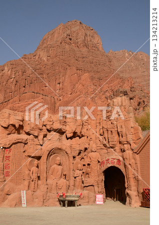 Buddha statue sculpture on the cliff face of the temple in front of the entrance gate at the Tianshan Grand Canyon, or Kesileya Grand Canyon, is a stunning natural feature in Xinjiang, China,  134213214