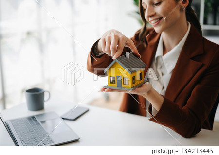 Female real estate agent is use hands to protect red roof for the concept Female real estate agent is use hands to protect red roof for the concept 134213445