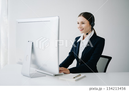 Serious call center operator in wireless headset talking with customer, woman in headphones 134213456