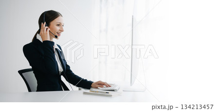 Serious call center operator in wireless headset talking with customer, woman in headphones Serious call center operator in wireless headset talking with customer, woman in headphones 134213457