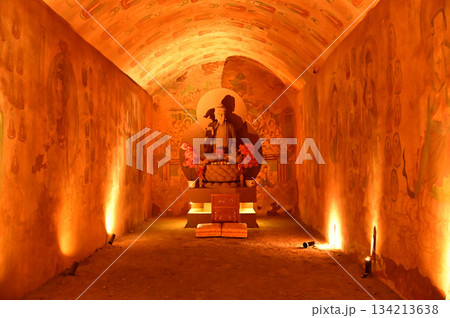 Buddha statue sculpture in a cave of the temple in front of the entrance gate at the Tianshan Grand Canyon, or Kesileya Grand Canyon, is a stunning natural feature in Xinjiang, China. 134213638