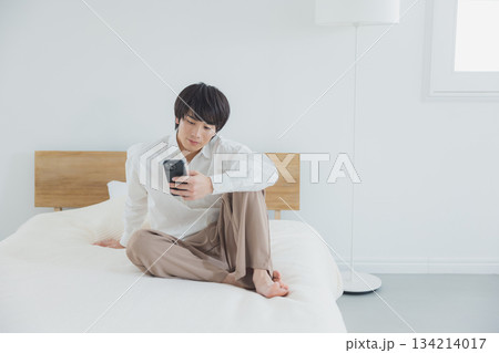 ベッドでスマホを見る男性　 134214017
