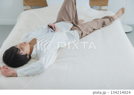 ベッドでスマホを見る男性　 134214024