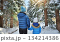 雪が降った森をあるく父親と娘の後ろ姿 134214386