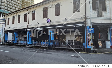 A heritage shophouse from 1927 with arched windows and outdoor bar seating blends classic architecture with modern nightlife, featuring beer signage  134214451