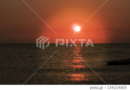 Sunset over calm sea orange sky with light trail horizontal Sunset over calm sea orange sky with light trail horizontal 134214803