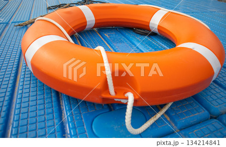 Orange lifebuoy on blue pontoon water safety close up horizontal 134214841
