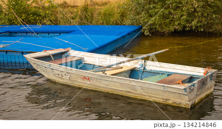 Aluminum rowboat by blue pontoon on water horizontal 134214846