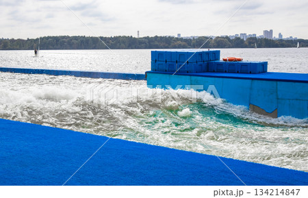 Artificial training wave for surfers on lake with blue platform 134214847