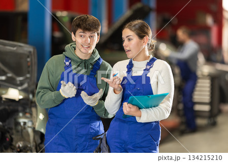 Car service manager discusses car repair problems with mechanic. He takes notes on paper 134215210