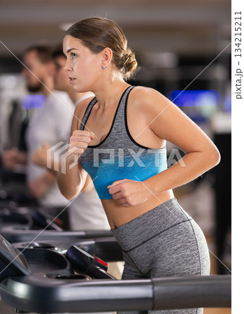 Focused girl works out with treadmill during class at fitness club 134215211