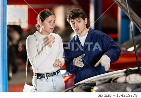 Mechanic checking young woman client car in car service center Mechanic checking young woman client car in car service center 134215279